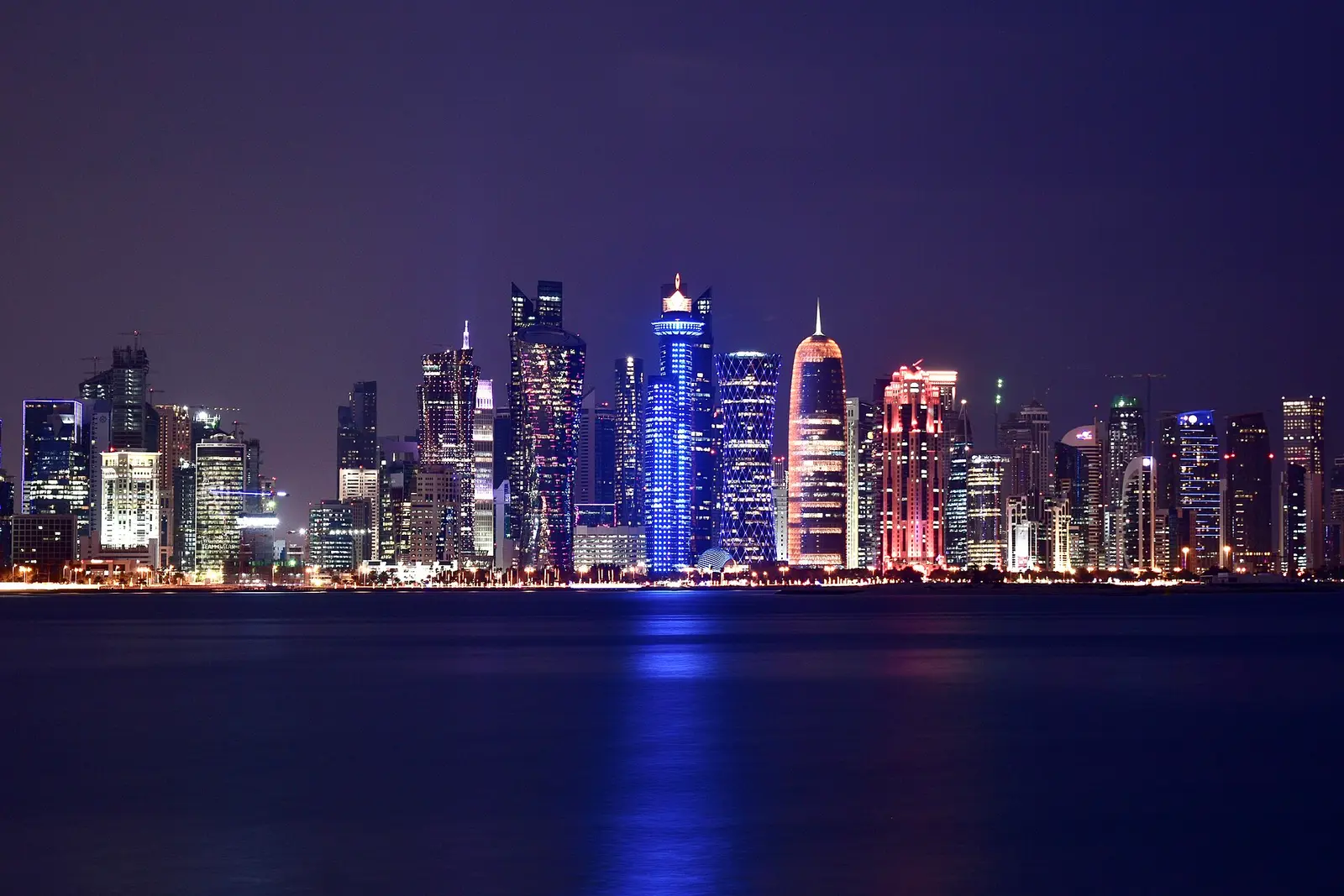 Lit West Bay skyscrapers reflected in the bay at night in Doha