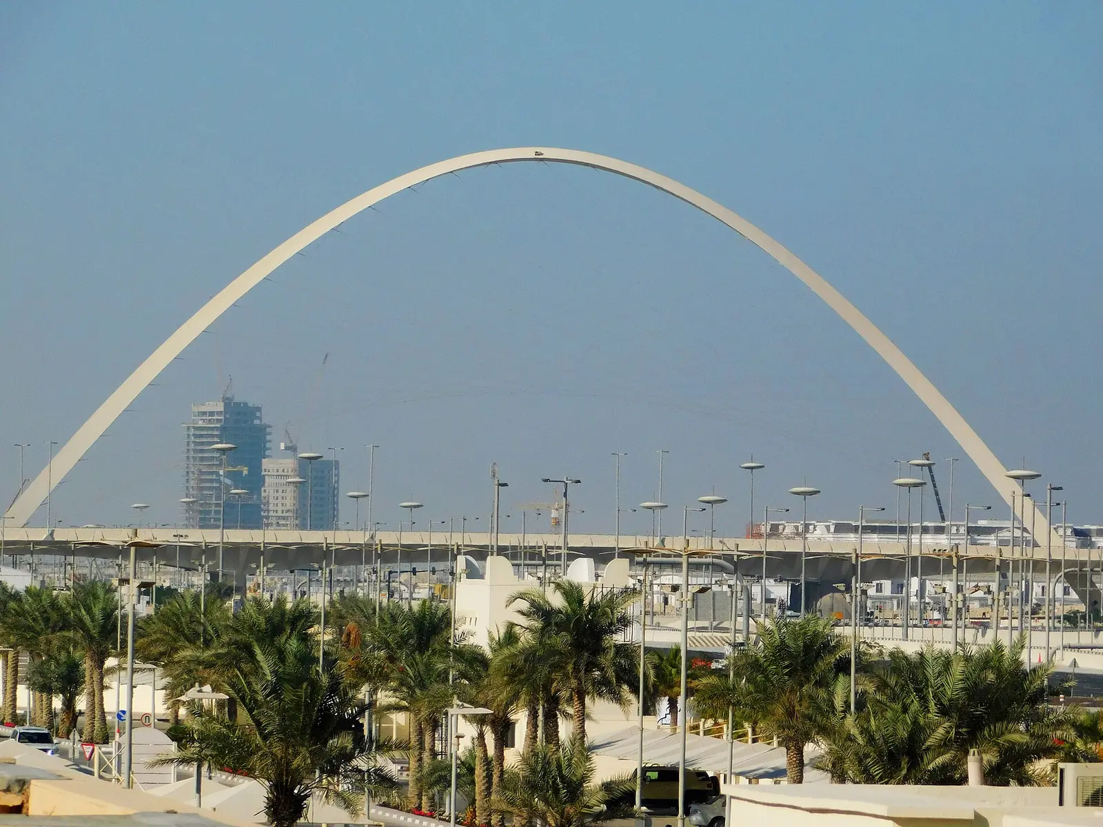 White steel arch over the road at Lusail Marina with marina and towers behind