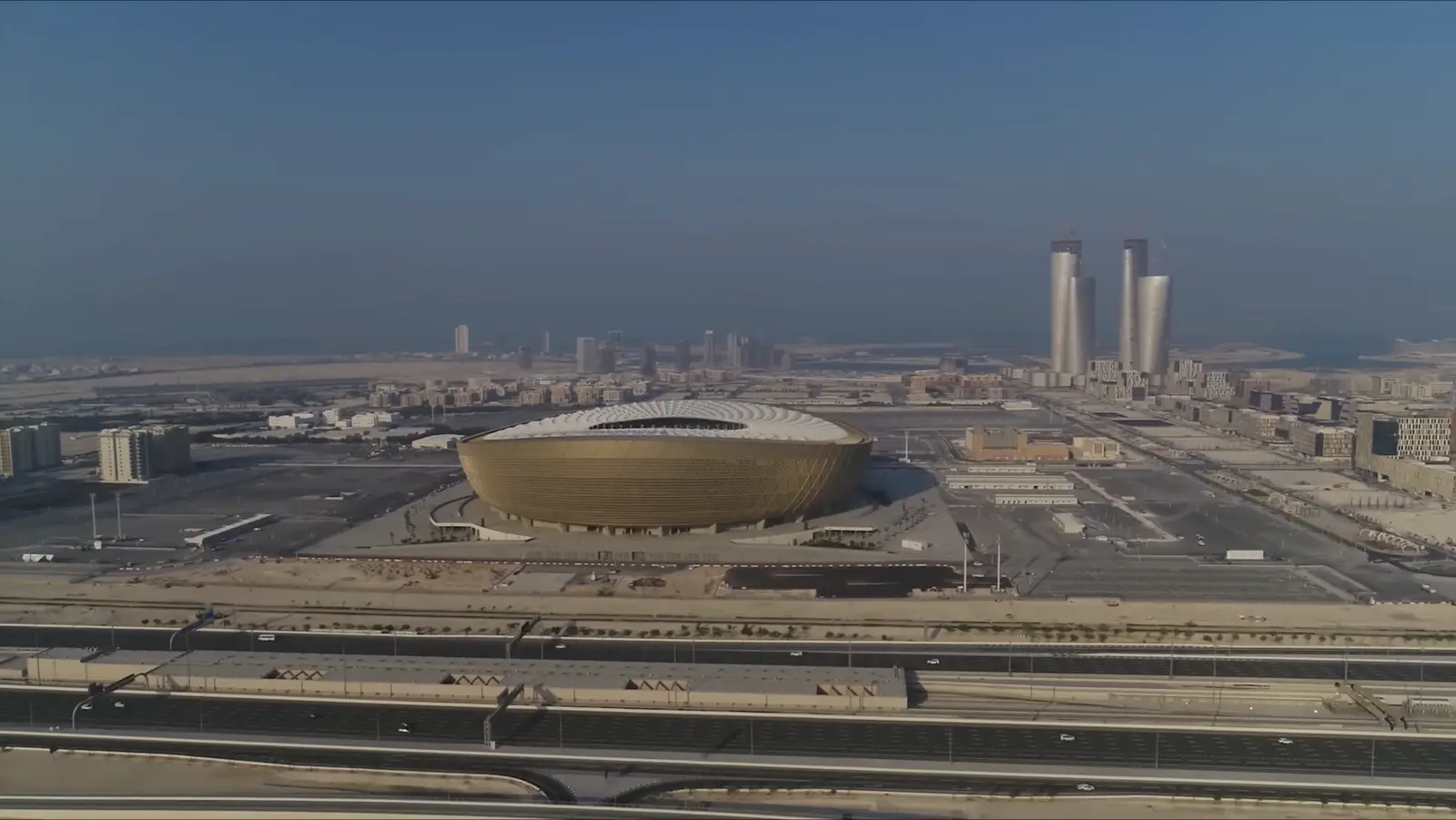 Aerial view of Lusail Stadium and the towers behind it in daylight