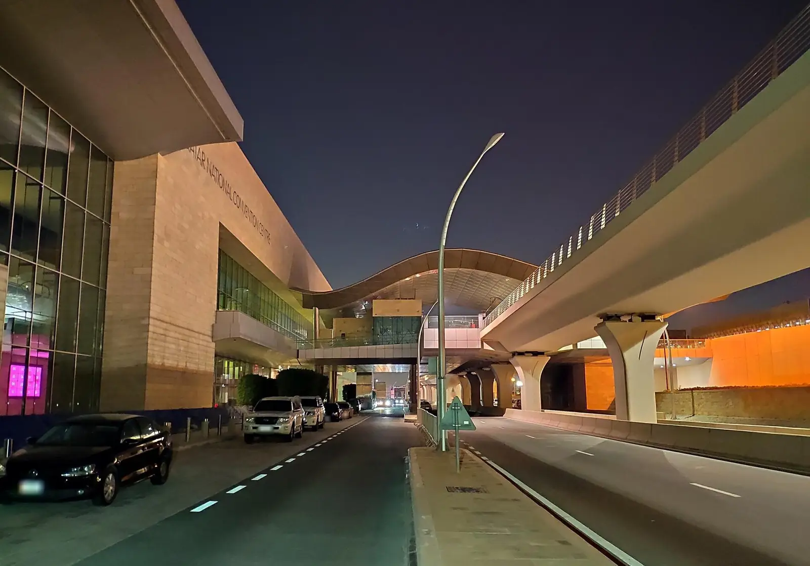 Front of the Qatar National Convention Centre at dusk with road and metro line